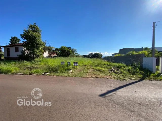 Vista externa de uma propriedade com terreno gramado e estrada no primeiro plano.