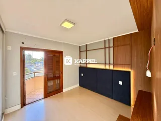 Foto interna de uma sala com piso de madeira e painel de madeira.