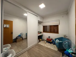 Vista interna de uma sala com piso de madeira e uma janela com persianas.