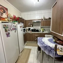 Foto interna de uma cozinha com armários brancos e eletrodomésticos.