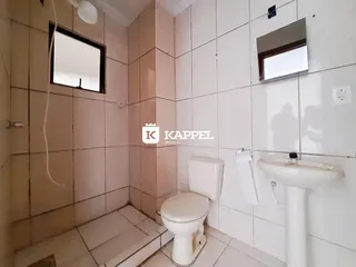 Banheiro com revestimento de azulejos brancos e louças brancas.