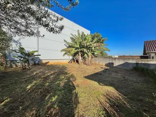 Fachada de uma residência com jardim gramado e vegetação ao ar livre.