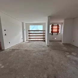 Vista interna de um ambiente com piso de concreto e parede branca.