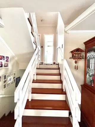 Vista de uma escadaria interna com corrimãos brancos e degraus de madeira.