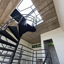 Foto de uma escadaria metálica em um ambiente interno com teto de textura.