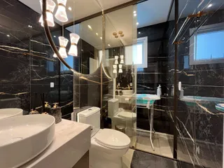 Banheiro moderno com revestimento de mármore preto e branco e iluminação sofisticada.