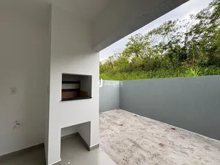 Vista interna de uma área com paredes brancas e piso de concreto.