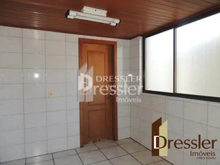 Interior de um cômodo com paredes brancas e porta de madeira em um imóvel em Lajeado.