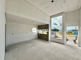 Esta é uma sala ampla com piso de concreto e paredes brancas, mostrando um espaço em construção.