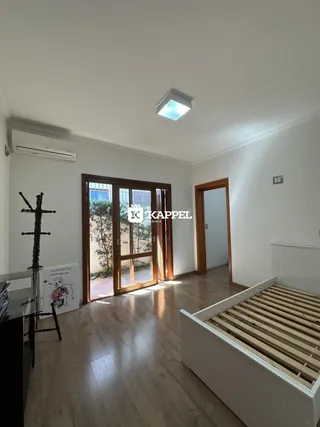 Uma sala de estar com piso de madeira e portas de vidro que dão acesso a um pátio externo.