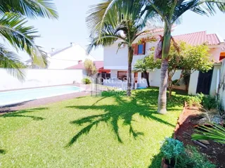 Fachada de uma residência com gramado e piscina no exterior.