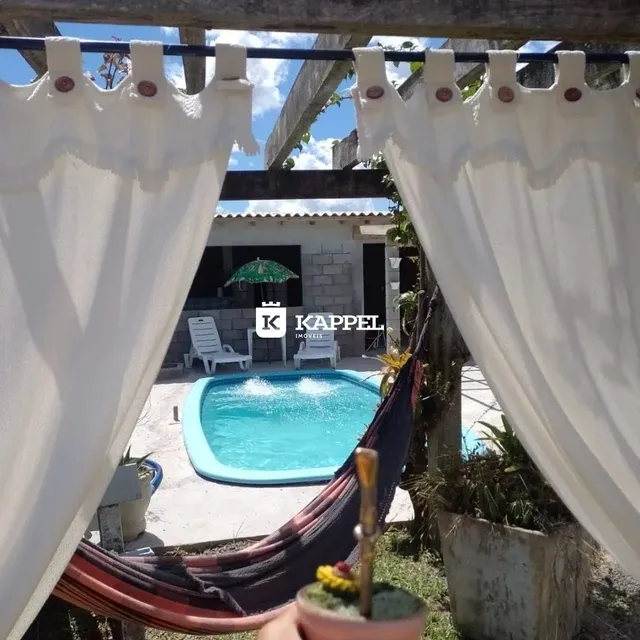 Foto de uma piscina externa em um quintal com cortinas brancas.