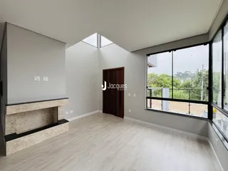 Sala de estar com piso de madeira clara e janela com vista para a vegetação.