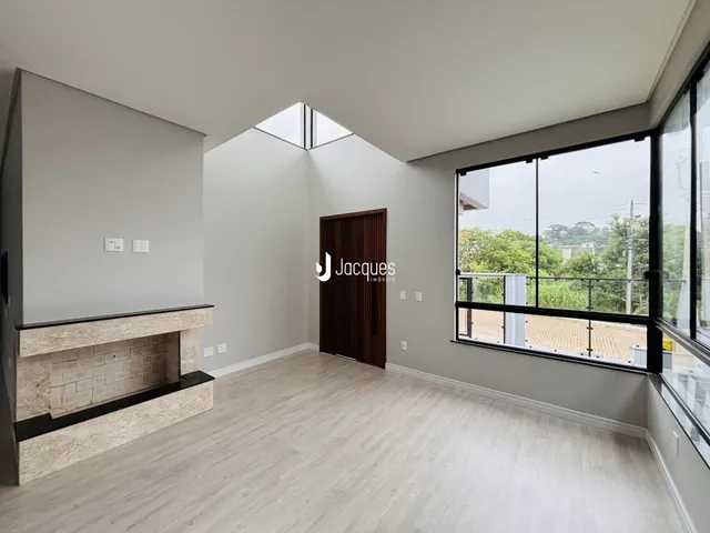 Sala de estar com piso de madeira clara e janela com vista para a vegetação.