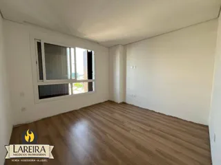 Ambiente interno de um imóvel com piso de madeira e grande janela.