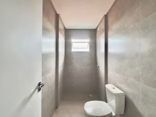 Corredor de banheiro com paredes de azulejo cinza e um vaso sanitário branco.