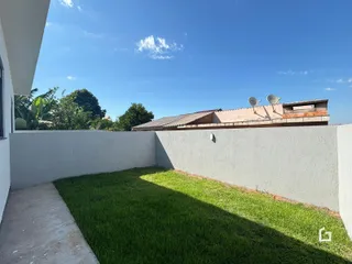 Vista lateral de um quintal com gramado e muro branco.