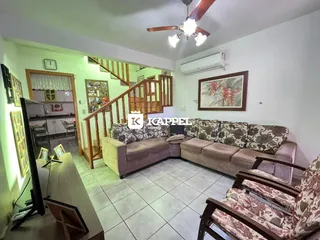 Sala de estar com sofá e escadaria de madeira em apartamento no Brasil.