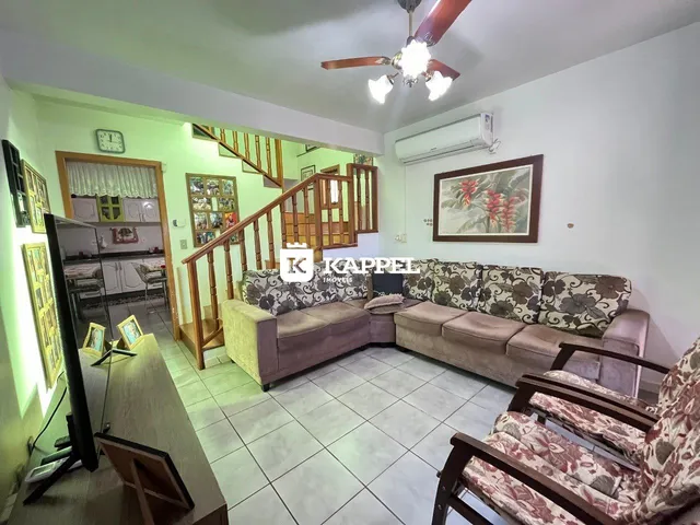 Sala de estar com sofá e escadaria de madeira em apartamento no Brasil.