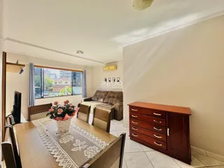 Sala de jantar com sofá e móveis de madeira em um imóvel no Brasil.