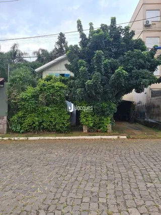 Vista externa da propriedade com paisagismo e pavimento de tijolos.