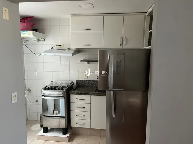Cozinha com armários brancos e revestimento de cerâmica.