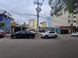 Vista externa de uma rua com veículos estacionados e postes de energia.