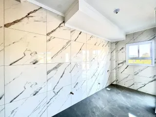 Parede interna com revestimento de mármore branco e piso cinza.