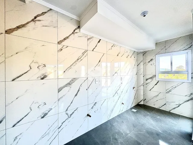 Parede interna com revestimento de mármore branco e piso cinza.
