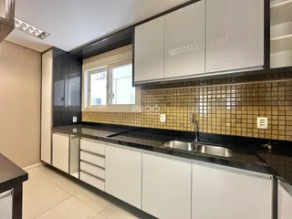 Foto de uma cozinha com armários brancos e revestimento de azulejos marrons.