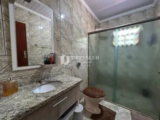 Banheiro com bancada de granito e box de vidro.