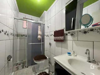 Foto interna de um banheiro com revestimento cerâmico branco.