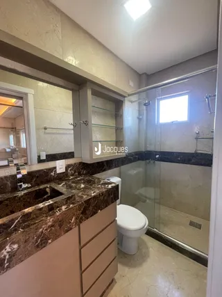 Foto de um banheiro com bancada de mármore e box de vidro.