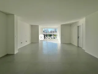 Vista interna de um ambiente amplo com piso claro e grande janela para a paisagem urbana.