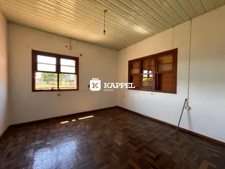 Sala ampla com piso de madeira e janelas grandes.