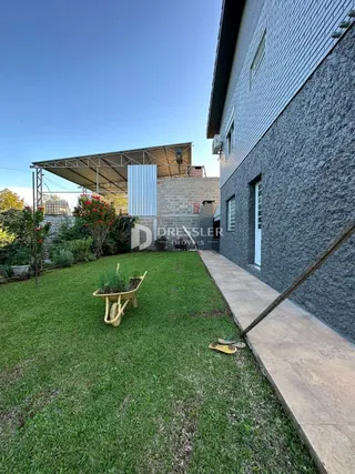 Vista externa de uma residência com jardim gramado e estrutura de madeira.