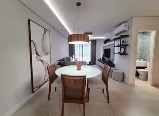 Sala de estar com mesa redonda e cadeiras de madeira.
