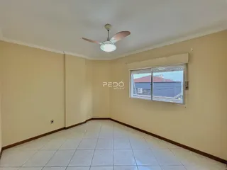 Interior de um corredor com piso de cerâmica clara e paredes bege.