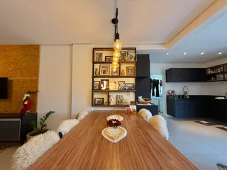 Vista de uma sala de jantar com mesa de madeira no interior de uma residência.