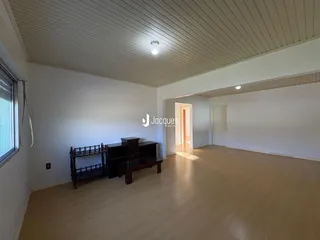 Ambiente interno de uma sala com piso de madeira clara e teto de painéis brancos.