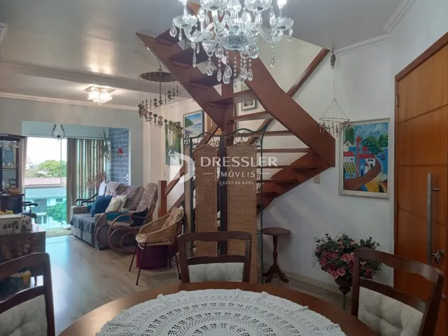Sala de estar com escadaria de madeira e vista para o exterior.