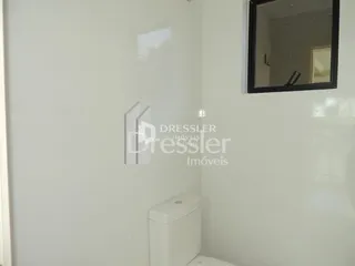Parede branca de um ambiente com vaso sanitário.
