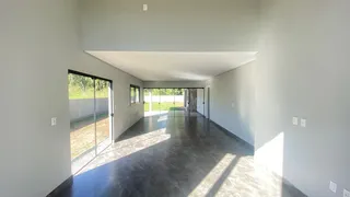 Hall de entrada amplo com piso escuro e portas de vidro que dão acesso ao exterior.
