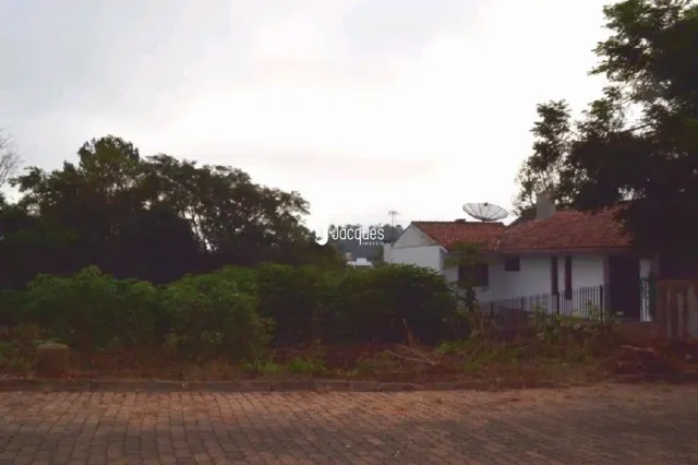 Fachada de uma residência parcialmente oculta por vegetação densa.