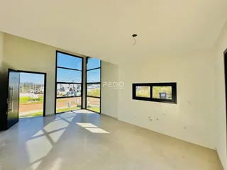 Vista interna de um ambiente com grandes portas de vidro e piso de concreto.