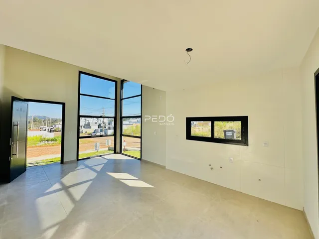 Vista interna de um ambiente com grandes portas de vidro e piso de concreto.