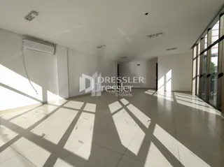 Interior de um espaço amplo com piso claro e luz natural forte.