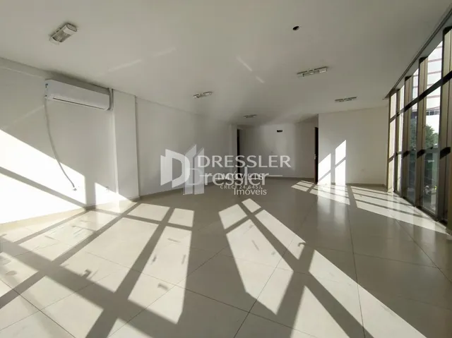 Interior de um espaço amplo com piso claro e luz natural forte.
