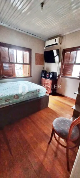 Quarto com cama e piso de madeira em uma residência.