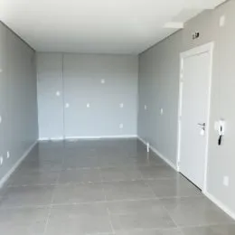 Imagem de um ambiente interno longo com piso de cerâmica e paredes brancas.